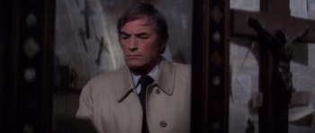 Movie still from “The Omen” (1976), directed by Richard Donner – A man in a trench coat and a tie looking into a mirror; Close Up shot, Over the shoulder angle