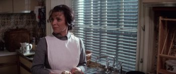 Movie still from “The Omen” (1976), directed by Richard Donner – A woman standing in front of a kitchen sink; Medium shot, Over the shoulder angle