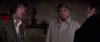 Movie still from “The Omen” (1976), directed by Richard Donner – A man wearing a white coat standing in a room; Medium shot, Over the shoulder angle
