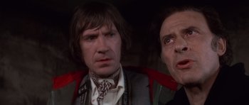 Movie still from “The Omen” (1976), directed by Richard Donner – A man and a woman standing next to each other in a room; Close Up shot, Low angle