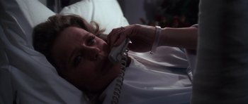 Movie still from “The Omen” (1976), directed by Richard Donner – A woman laying in a bed talking on a phone; Close Up shot, High angle