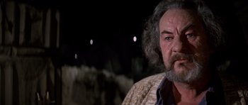 Movie still from “The Omen” (1976), directed by Richard Donner – An older man with long grey hair and a beard; Close Up shot, Over the shoulder angle