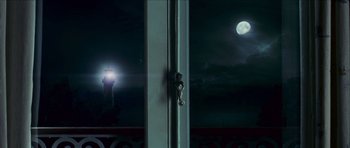 Movie still from “The Orphanage” (2007), directed by J.A. Bayona – A view of a lighthouse through a window at night; Extreme Wide shot, Low angle
