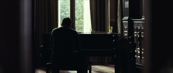 Movie still from “The Orphanage” (2007), directed by J.A. Bayona – A man sitting in front of an open window; Wide shot, Over the shoulder angle