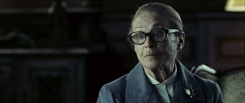Movie still from “The Orphanage” (2007), directed by J.A. Bayona – An older woman wearing glasses and a jacket; Close Up shot, Over the shoulder angle
