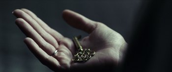 Movie still from “The Orphanage” (2007), directed by J.A. Bayona – A hand holding a key and a wedding ring; Extreme Close Up shot, High angle
