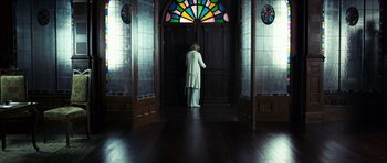 Movie still from “The Orphanage” (2007), directed by J.A. Bayona – A person standing in front of an open door; Wide shot, Low angle