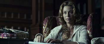 Movie still from “The Orphanage” (2007), directed by J.A. Bayona – A woman sitting at a table looking at the camera; Close Up shot, Over the shoulder angle