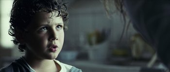 Movie still from “The Orphanage” (2007), directed by J.A. Bayona – A young boy with curly hair stares into the distance; Close Up shot, Over the shoulder angle