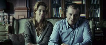 Movie still from “The Orphanage” (2007), directed by J.A. Bayona – A man and a woman sitting next to each other on a couch; Medium shot, Low angle