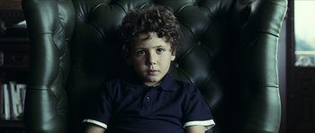 Movie still from “The Orphanage” (2007), directed by J.A. Bayona – A young boy sitting in a black chair; Close Up shot, High angle