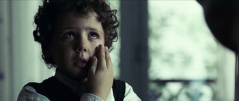 Movie still from “The Orphanage” (2007), directed by J.A. Bayona – A young boy holding his hand up to his face; Close Up shot, Over the shoulder angle