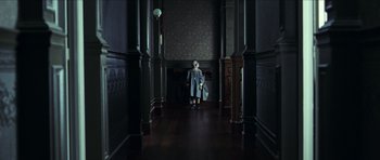 Movie still from “The Orphanage” (2007), directed by J.A. Bayona – A creepy doll is standing in a dark hallway; Wide shot, Low angle