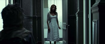 Movie still from “The Orphanage” (2007), directed by J.A. Bayona – A woman standing in front of an open door; Wide shot, Low angle
