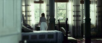 Movie still from “The Orphanage” (2007), directed by J.A. Bayona – A woman standing in front of a window in a room; Wide shot, Low angle