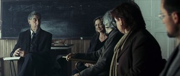 Movie still from “The Orphanage” (2007), directed by J.A. Bayona – A group of people sitting in a room together; Medium shot, Over the shoulder angle