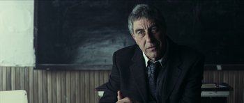 Movie still from “The Orphanage” (2007), directed by J.A. Bayona – An older man wearing a suit and tie; Close Up shot, Over the shoulder angle