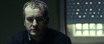Movie still from “The Orphanage” (2007), directed by J.A. Bayona – A person wearing glasses and a black shirt; Close Up shot, Low angle