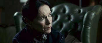Movie still from “The Orphanage” (2007), directed by J.A. Bayona – An older woman sitting in a chair looking off to her left; Close Up shot, Over the shoulder angle