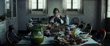 Movie still from “The Orphanage” (2007), directed by J.A. Bayona – A woman sitting at a table with a lot of food; Medium shot, Over the shoulder angle