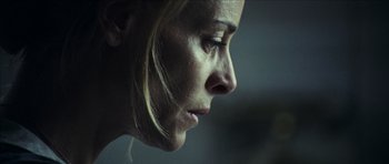 Movie still from “The Orphanage” (2007), directed by J.A. Bayona – A woman's face in a dimly - lit room; Close Up shot, Low angle