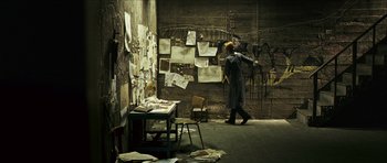 Movie still from “The Orphanage” (2007), directed by J.A. Bayona – A man standing in a room with papers on the wall; Wide shot, High angle