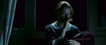Movie still from “The Orphanage” (2007), directed by J.A. Bayona – A woman sitting in front of a window with her hands clasped together; Close Up shot, Low angle