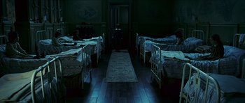 Movie still from “The Orphanage” (2007), directed by J.A. Bayona – Many beds in this room with a person standing in front of them; Wide shot, High angle