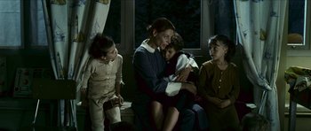 Movie still from “The Orphanage” (2007), directed by J.A. Bayona – A group of people sitting in a dark room; Medium shot, Over the shoulder angle