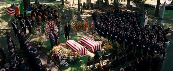 Movie still from “The Other Guys” (2010), directed by Adam McKay – A group of people standing around a grave with coffins; Wide shot, High angle