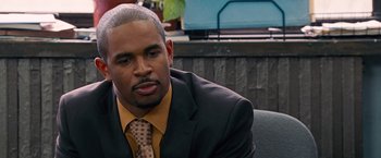 Movie still from “The Other Guys” (2010), directed by Adam McKay – A man in a suit and tie sitting in a chair; Close Up shot, Over the shoulder angle