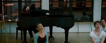 Movie still from “The Other Guys” (2010), directed by Adam McKay – A woman sitting in front of a grand piano; Medium shot, Over the shoulder angle