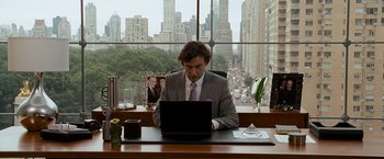 Movie still from “The Other Guys” (2010), directed by Adam McKay – A man sitting at a desk using a computer in front of a window; Medium shot, Over the shoulder angle