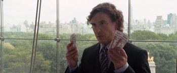Movie still from “The Other Guys” (2010), directed by Adam McKay – A man in a suit and tie holding up two tickets; Medium shot, Over the shoulder angle