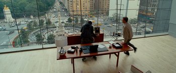 Movie still from “The Other Guys” (2010), directed by Adam McKay – A man sitting at a desk in front of a large window; Wide shot, High angle
