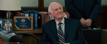 Movie still from “The Other Guys” (2010), directed by Adam McKay – An older man wearing a suit and tie sitting at a desk; Close Up shot, Over the shoulder angle