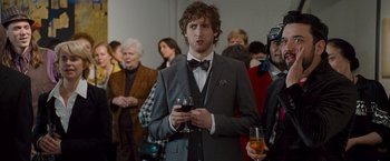 Movie still from “The Other Guys” (2010), directed by Adam McKay – A man holding a glass of wine in front of a crowd; Medium shot, Over the shoulder angle