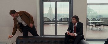 Movie still from “The Other Guys” (2010), directed by Adam McKay – Two men in suits are sitting on a couch in front of a window with an empire state building in the background; Medium shot, Over the shoulder angle