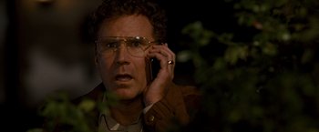 Movie still from “The Other Guys” (2010), directed by Adam McKay – A man with glasses is talking on a cell phone; Close Up shot, High angle