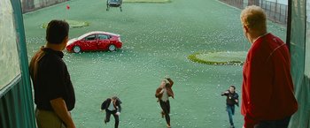 Movie still from “The Other Guys” (2010), directed by Adam McKay – Two people running in a field with a red car in the background; Extreme Wide shot, High angle