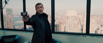 Movie still from “The Other Guys” (2010), directed by Adam McKay – A man standing in front of a window with a city view; Medium shot, Over the shoulder angle