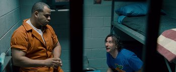 Movie still from “The Other Guys” (2010), directed by Adam McKay – A man sitting next to another man in a room; Medium shot, Over the shoulder angle