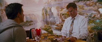 Movie still from “The Other Guys” (2010), directed by Adam McKay – A man sitting at a table with a plate of food in front of him; Medium shot, Over the shoulder angle