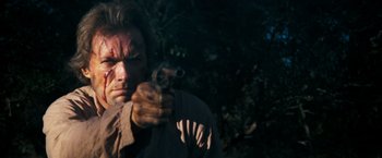 Movie still from “The Outlaw Josey Wales” (1976), directed by Clint Eastwood – A man holding a gun while standing in the dark; Close Up shot, Low angle