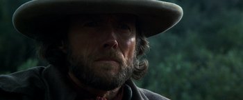 Movie still from “The Outlaw Josey Wales” (1976), directed by Clint Eastwood – A person wearing a hat with trees in the background; Close Up shot, Low angle