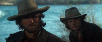 Movie still from “The Outlaw Josey Wales” (1976), directed by Clint Eastwood – A man and a woman wearing hats near a body of water; Close Up shot, Low angle