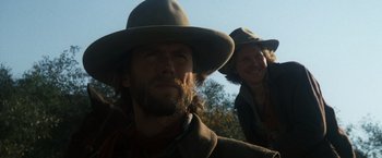 Movie still from “The Outlaw Josey Wales” (1976), directed by Clint Eastwood – A man and a woman wearing a hat and looking at the camera; Close Up shot, Low angle