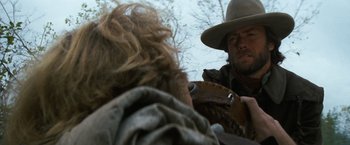 Movie still from “The Outlaw Josey Wales” (1976), directed by Clint Eastwood – A man in a cowboy hat is playing a guitar; Close Up shot, Over the shoulder angle