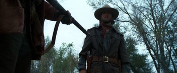 Movie still from “The Outlaw Josey Wales” (1976), directed by Clint Eastwood – A man holding a rifle in front of another man; Medium shot, Low angle