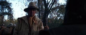 Movie still from “The Outlaw Josey Wales” (1976), directed by Clint Eastwood – An old man holding a gun while wearing a hat; Medium shot, Low angle